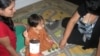 With Vijan's mother Bhawana looking on, family support worker Tina Fontaine uses play time to help develop the baby's motor skills. (VOA/J. Taboh) 