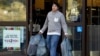 FILE - A man carries bags out of a department store, in Alameda, California, Dec. 17, 2015. Stronger-than-expected consumer spending helps ease fears of a U.S. recession.