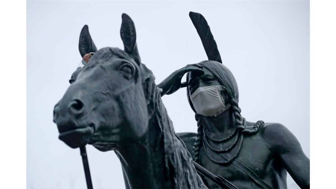 A statue of a Sioux Indian scout wears a face mask as it stands on a bluff overlooking Kansas City, Mo., March 26, 2020.