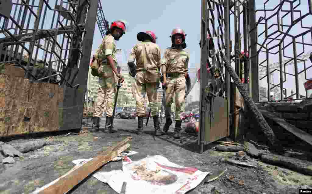2013 年8月15日，开罗纳赛尔城，被废黜的埃及总统穆尔西的海报被扔在地上，军警站在被焚烧的清真寺外面