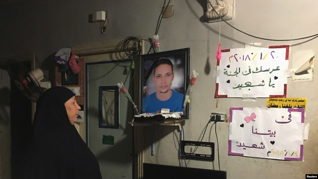 FILE - Lotfy Ibrahim’s mother, Tahany, looks at a photograph of her son at home in Kafr al-Sheikh, Egypt, Jan. 13, 2019. 