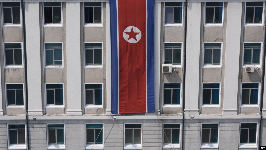 FILE - A pedestrian walks past a North Korean flag displayed on a building in Pyongyang, North Korea, April 12, 2019.