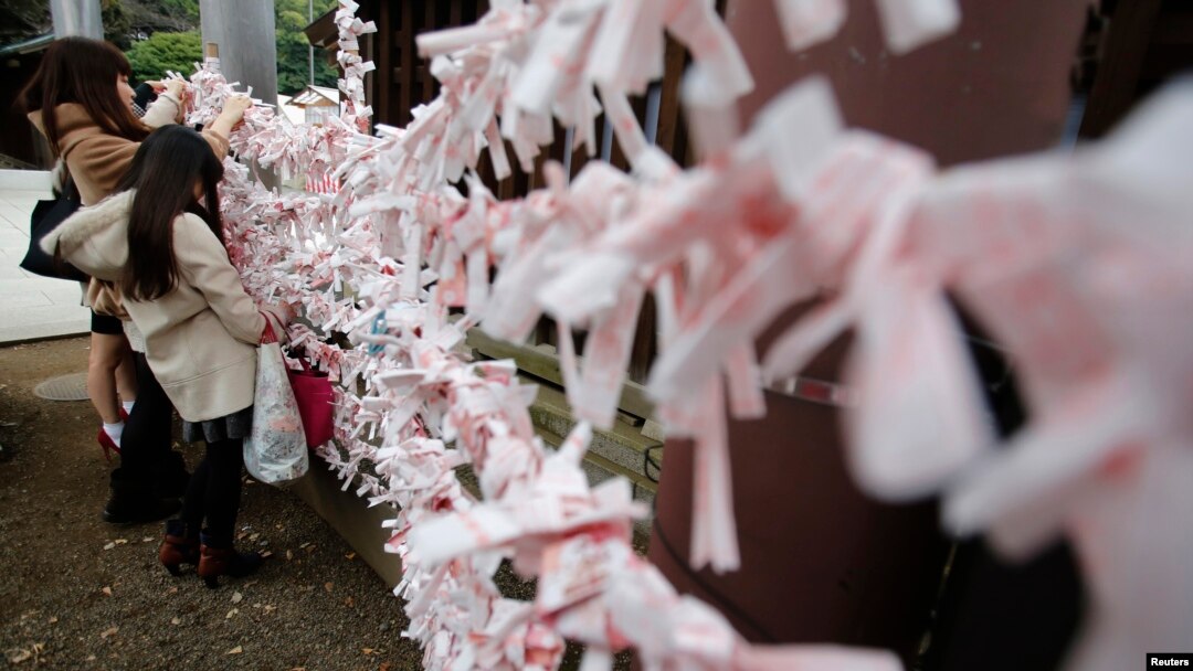 FILE - Visitors hang fortune blessing papers at Yasukuni Shrine in Tokyo, Dec. 26, 2013. 