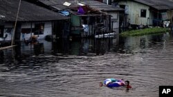 曼谷居民带着孩子在上涨的运河中涉水而行