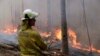 A firefighter keeps an eye on a controlled fire as they work at building a containment line at a wildfire near Bodalla, Australia, Jan. 12, 2020. 