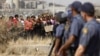 Police look on as women carry placards in protest against the killing of miners by the South African police on Thursday, outside a South African mine in Rustenburg, 100 kilometers northwest of Johannesburg, August 17, 2012.