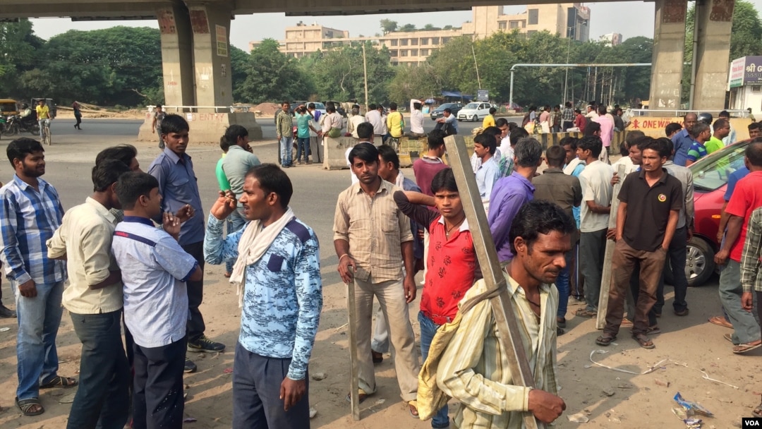 Scores of daily wage workers wait at a major street intersection in the business hub of Gurgaon near New Delhi hoping to find work. (A. Pasricha/VOA)