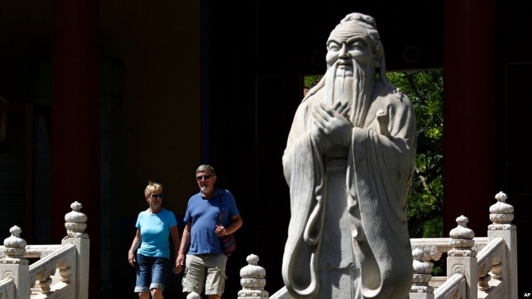 FILE - Tourists walk past a statue of philosopher Confucius in Beijing, May 28, 2019. At that time, China used five-day Confucian culture immersion courses for religious leaders as part of a campaign to extend government control over faith communities.