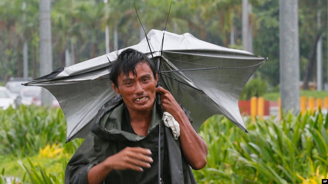 A man walks along a boulevard under the slight rain in Manila, Philippines, Oct. 16, 2016. Typhoon Sarika, with sustained winds of 130 kilometers (80) miles per hour and gusts of 220 kph (136mph), has slammed into the northeastern Philippines.