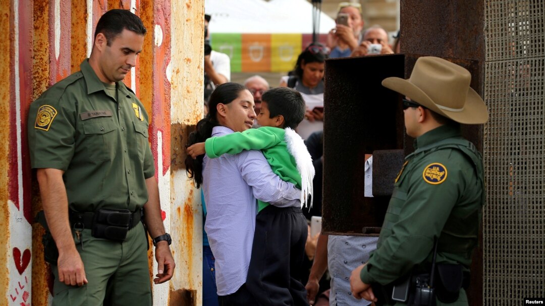 U.S. Border patrol agents stand at an open gate along the Mexico border to allow Luis Eduardo Hernandez-Bautista hug Ty'Jahnae Williams and his father Eduardo Hernandez (not in view), as part of Universal Children's Day at the Border Field State Park, California, Nov. 19, 2016. 