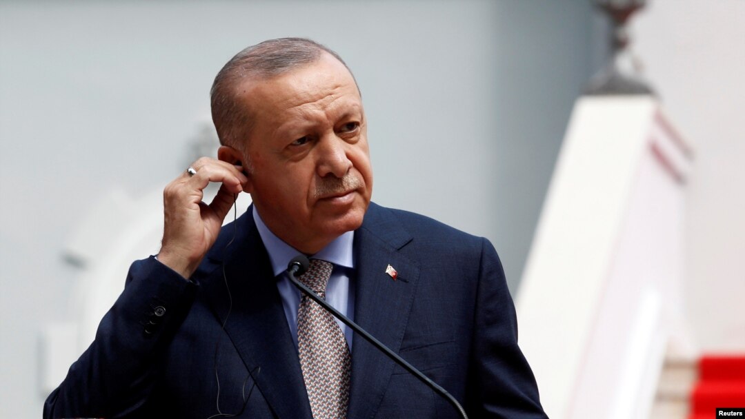 FILE - Turkish President Tayyip Erdogan adjusts earphones at a news conference.